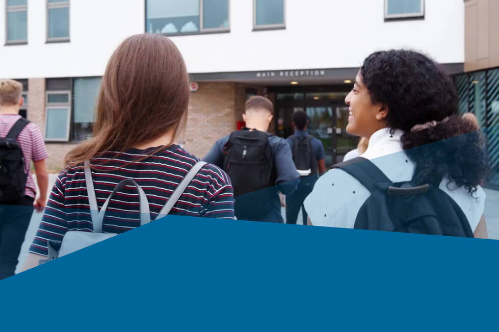 Students walking into a school. View is from the back.